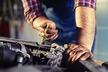 Hand of car mechanic check engine oil for maintenance.