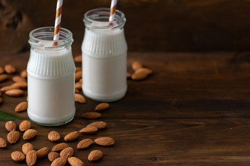 Almond milk with almond on a dark wooden table. Copy space