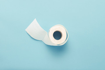 Roll of unfolded toilet paper on a blue background. Flat lay, top view