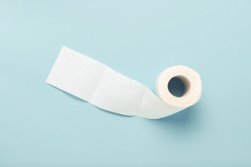 Roll of unfolded toilet paper on a blue background. Flat lay, top view