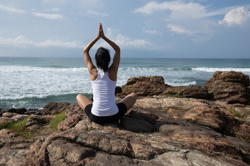 Fototapeta na wymiar Yoga woman clothing in white meditation at the seaside rock