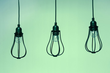 Three black incandescent light bulbs on green background. Decorative lighting.