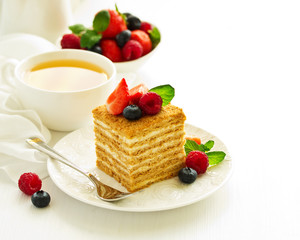 A piece of multi-layered honey cake with fresh berries. Selective focus