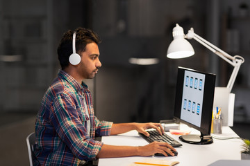 deadline, technology and people concept - creative man with headphones and computer listening to...