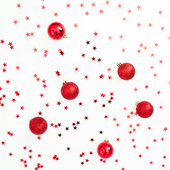 Christmas pattern made of red balls decoration with confetti on white background. Festive background. Flat lay, top view