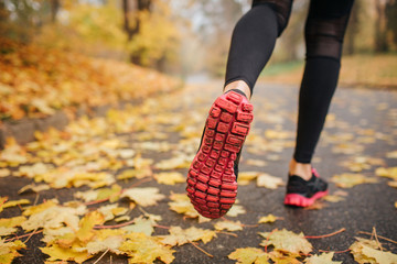 Picture of woman' legs in park on road. She runs. Woman wears black with red crosses and black...