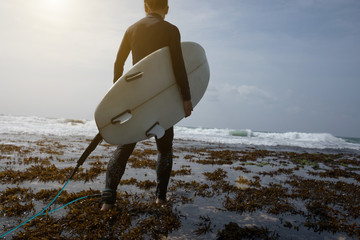 Fototapeta na wymiar woman surfer with surfboard walking on seaside reef