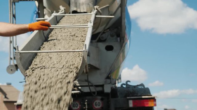 Work on pouring the foundation, the worker directs the chute from which the concrete flows