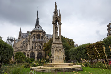Fototapeta na wymiar Apse of Notre-Dame de Paris and La fontaine de la Vierge from Square Jean-XXIII. Paris, France