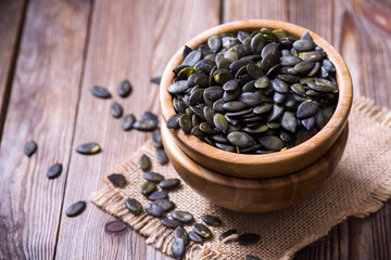 Pumpkin seeds on wooden background, healthy vegan ingredient or snack, nutrition concept