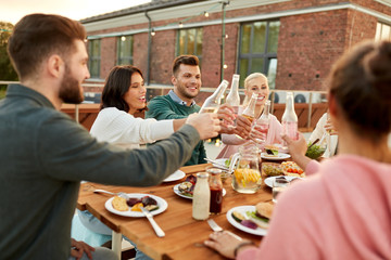 leisure and people concept - happy friends toasting drinks at rooftop party in summer