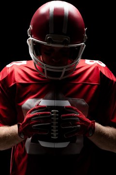 American football player with helmat looking at rugby ball