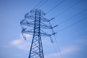 Fototapeta premium High voltage lines and power pylons over the blue sky.