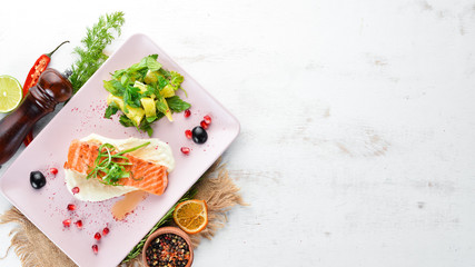 Baked salmon fillet with vegetables on a plate. On a wooden background. Top view. Free space for your text.