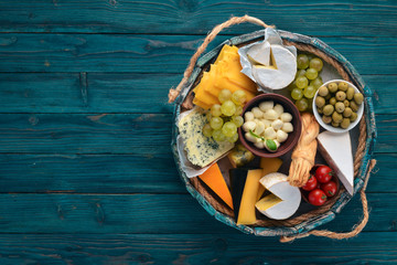 A set of cheese in a wooden box. Parmesan, Mamasam, Mozzarella, Brie, Feta. Top view. On a wooden background. Free space for your text.