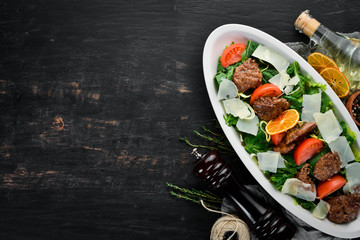 Salad with goose liver, spinach, tomatoes and parmesan cheese. On a wooden background. Top view. Free copy space