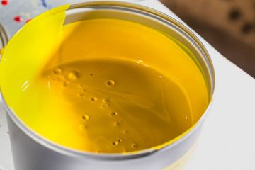 Open jar with yellow printing ink. CMYK printing ink.