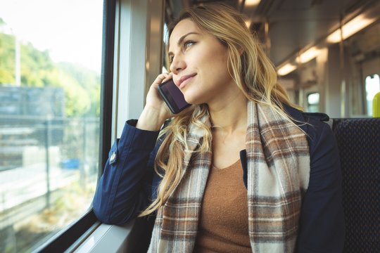 Blond pregnant woman talking on mobile phone while travelling in train