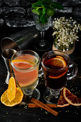 Hot wine with citrus fruit. Winter and autumn traditional cocktails. On a black wooden background. Free copy space. Top view.