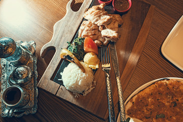 Turkish dish with rise, chiken, sause, pizza and coffee in silver cup holder on the restaurant table