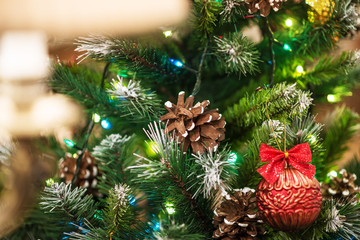 Obraz na płótnie Canvas Close-up green Christmas tree/ Close-up green Christmas tree decorated with toys, balls, cones and a garland.