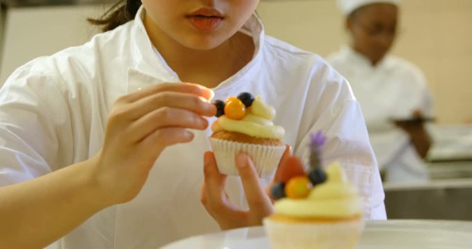 Female chef garnishing muffins in kitchen 4k
