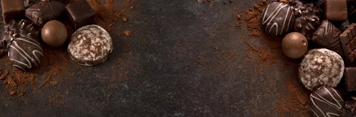 Stoff pro Meter Schokoladenkekse und Pralinen für eine Urlaubsveranstaltung auf dunklem Schieferhintergrund mit großem Kopierraum, breitem Panorama-Bannerformat © Maren Winter