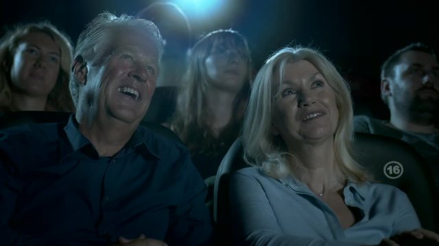 Older Couple At The Movie Theatre Laughing At A Comedy Film.