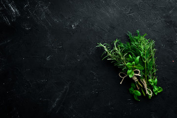 Fresh green spices and herbs. Dill, parsley, rosemary. On a black stone background. Top view. Free copy space.