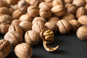 Halved and whole walnuts on black background, side view. Close-up. Selective focus.