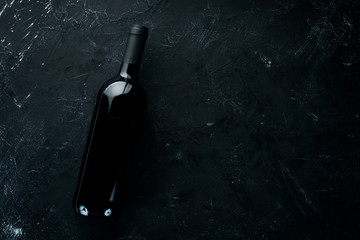 A bottle of red wine on a black stone background. Top view. Free copy space.