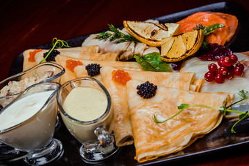 Pancakes with red and black caviar, with red fish and various sauces
