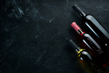 Set A bottle of white wine, red and rose wine on a black stone background. Top view. Free copy...