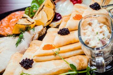 Pancakes with red and black caviar, with red fish and various sauces