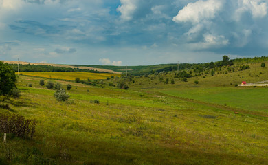 Fototapeta na wymiar rural landscape. hills and ravines in crops under a stormy sky. summer in the countryside