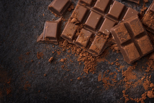 chocolate and cocoa powder on a dark slate background with copy space, high angle view from above