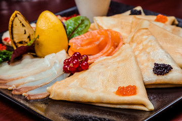 Pancakes with red and black caviar, with red fish and various sauces