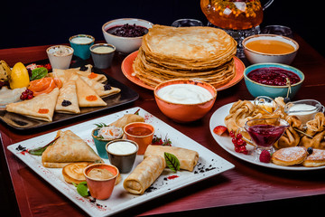 Shrovetide Maslenitsa festival meal. Russian pancakes blini with honey, fresh cream cheese and red...