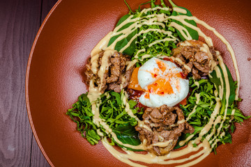 Hot appetizer salad with potatoes, meat, green peas, poached egg