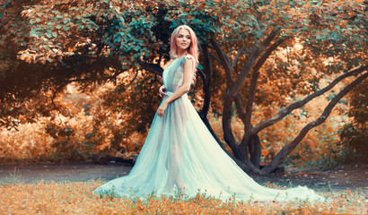 Fototapeta premium A nice girl is walking in a fairy forest, in a dress, in underwear. The blonde model is looking back