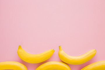 Beautiful, fresh, yellow bananas on pastel pink background. Mockup for different ideas. Empty place for text, quote or logo. Top view.