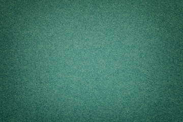 Texture of old dark green paper background, closeup. Structure of dense emerald cardboard.