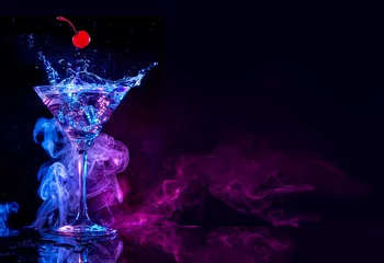Fotobehang Cocktail kers die in een martini valt die spettert op een blauwe en paarse rokerige achtergrond