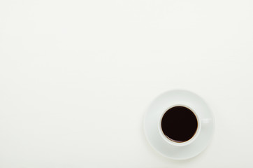A cup of hot black coffee on a saucer on a white background. Copy space, top view, flat lay