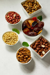 Various Nuts in a ceramic bowl and Dried Fruits on a light stone table. The Concept of a Healthy Dessert. Copy space.