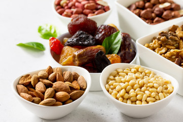 Various Nuts in a ceramic bowl and Dried Fruits on a light stone table. The Concept of a Healthy Dessert.