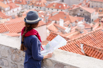 Dubrovnik traveler. Young woman with an old town map searching for right direction. Hat. Europe travel. 