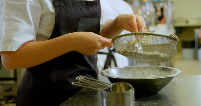 Chef staining white flour into metal bowl at restaurant 4k
