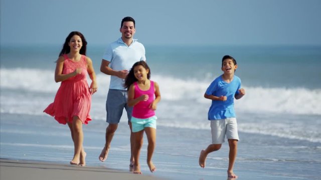 Happy Hispanic family spending leisure time on the beach outdoors