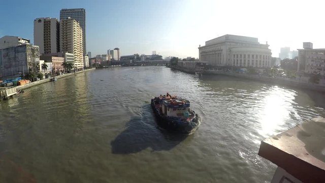 Carrier ship sailing toward bridge on huge, murky Pasig River early morning